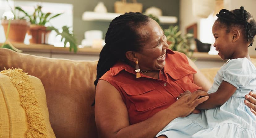 Grandmother smiles and holds her granddaughter.